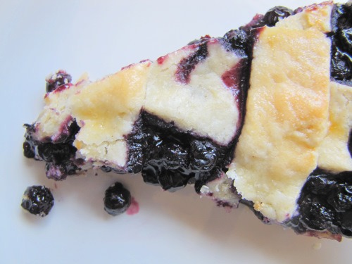 Bird's eye view of a slice of blueberry pie with a decorative lattice crust on a white background.