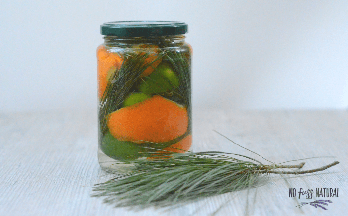orange peel and pine needles in glass jar with vinegar for green cleaning