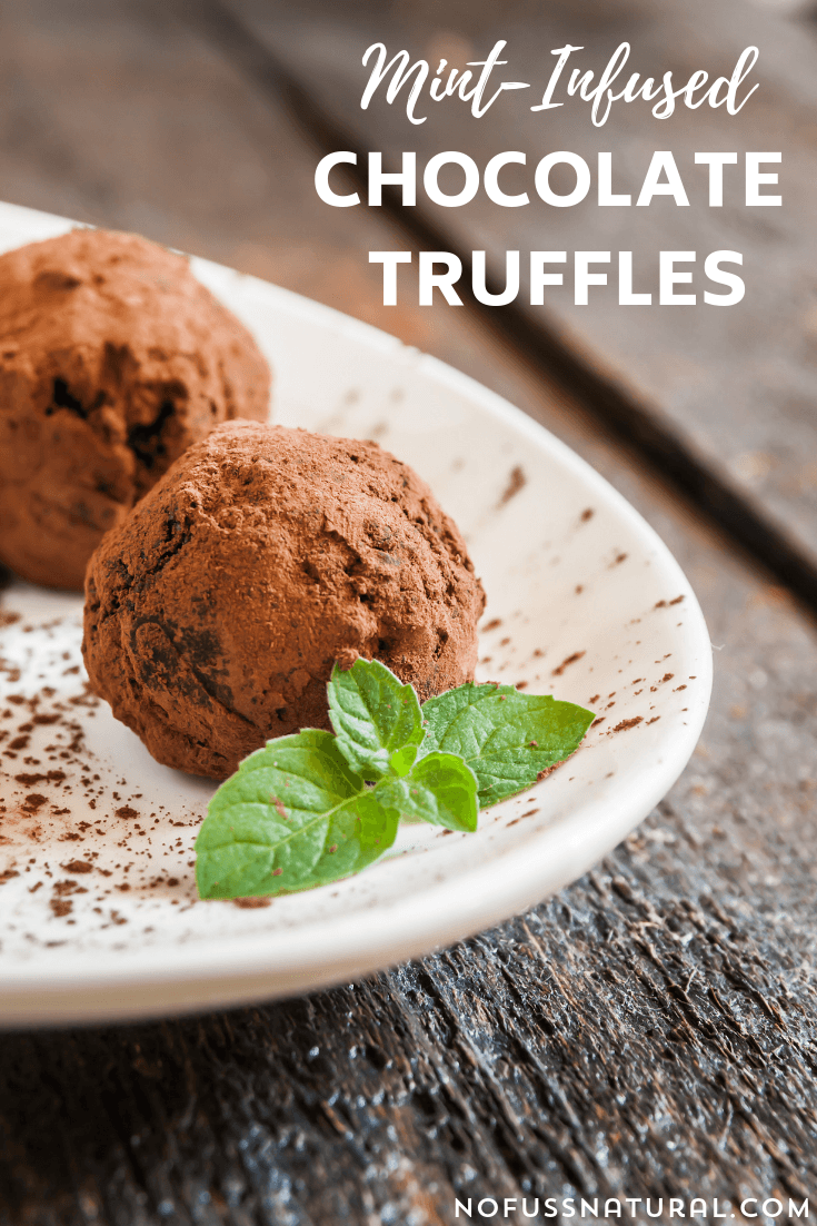 Image of chocolate truffles on a white plate. Plate is dusted with cocoa powder, and garnished with fresh mint leaves. Text overlay says, "Mint Infused Chocolate Truffles".