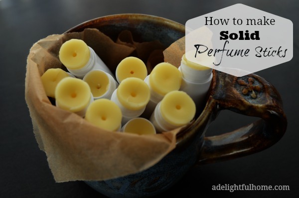 Image of a pottery mug full of opened lip balm tubes to show contents. Text overlay says, "How to Make Solid Perfume Sticks".