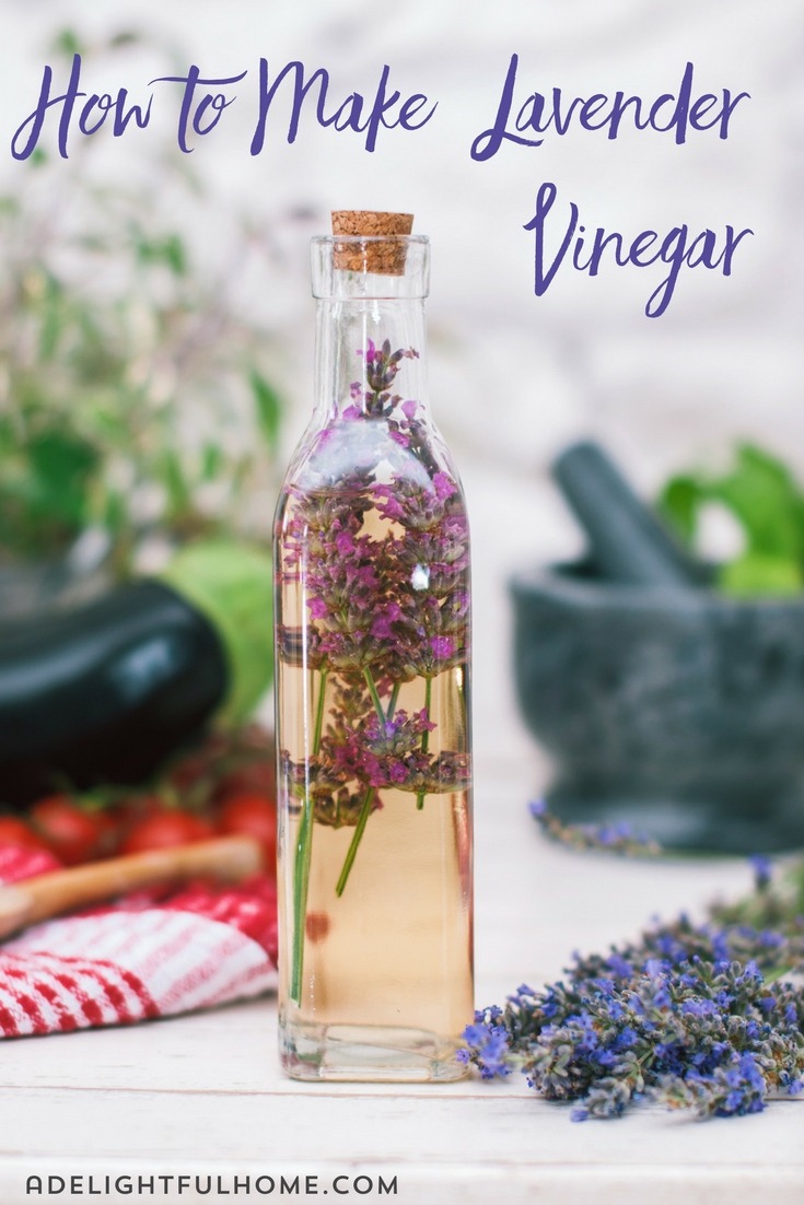 Glass bottle filled with lavender infused vinegar in a kitchen setting. Text overlay says, "How to Make Lavender Vinegar".