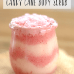 Image of a glass jar filled with red and white layers of body scrub. Text overlay says, "How to Make Candy Cane Body Scrub".
