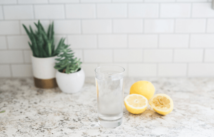 water in glass on counter with lemon