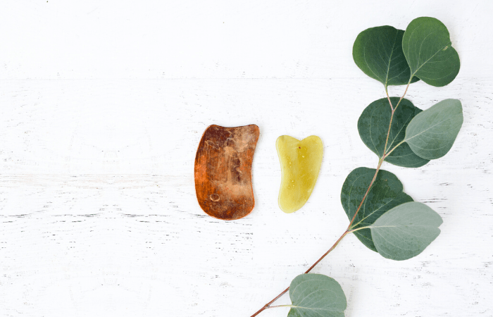 gua sha stones on table with eucalyptus leaf