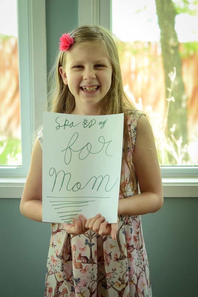 Kid with sign for Mothers day spa day